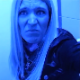 A mature, blonde woman records herself taking a shit while sitting on a toilet in a public restroom. No poop action or product is seen, but a soft-sounding dump is heard in several waves. Video has an odd, bluish hue. Over 5 minutes.